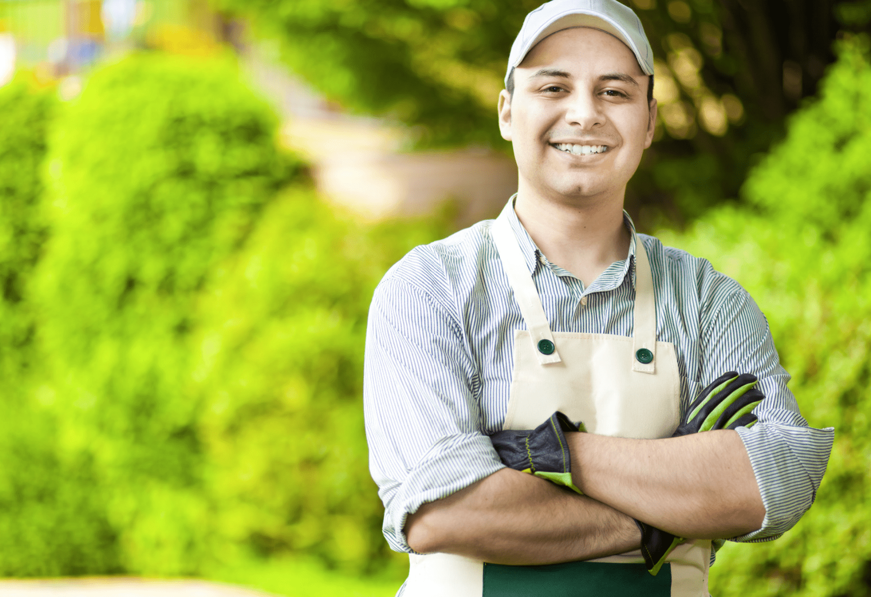 Portrait of a gardener wearing overalls with a hedge in the background